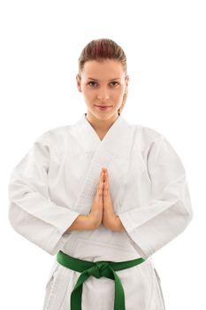 Beautiful female martial arts fighter in a white kimono with green belt holding her hands together in front of her, meditating or showing respect, isolated on white background.