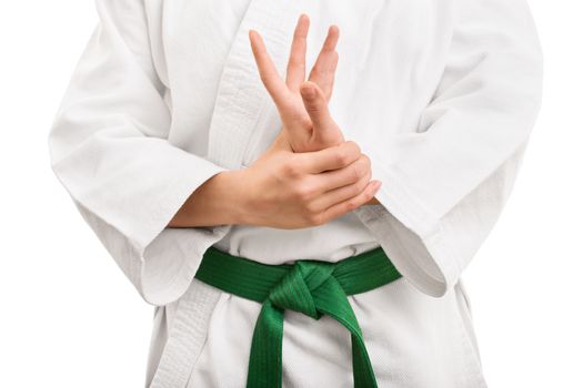 Mid section of a martial arts fighter in white kimono with green belt stretching and twisting her hand, isolated on white background.