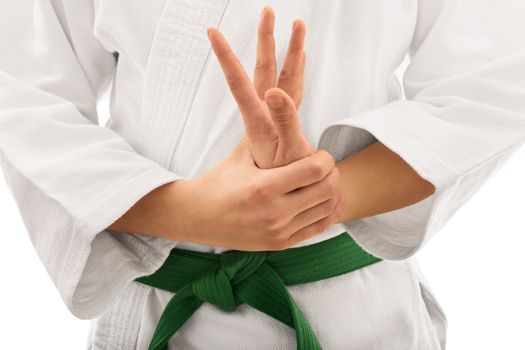 Close up shot of the mid section of a martial arts fighter in white kimono with green belt stretching and twisting her hand, isolated on white background.