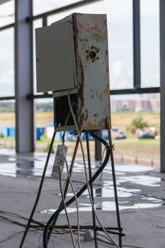 Bad metal electric switchboard on an unfinished construction site after rain.