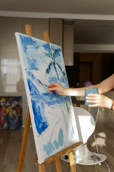 Woman paints a picture on canvas in her living room