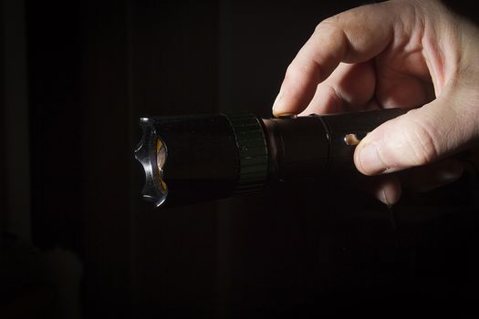 Male hand holds a black metal flashlight
