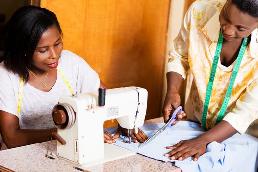 the seamstress cut the cloth to her  intern.