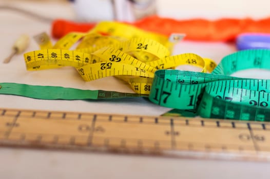 Ribbon meters, a screwdriver and a ruler arranged on a table in a sewing workshop.
