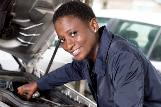 Young female mechanic repairs a car by putting the engine in good condition.