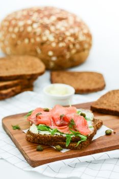 Smoked salmon sandwich with cheese, pistachio and salad leaves, brown breads