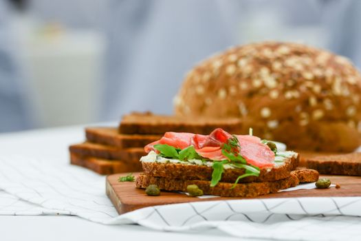 Smoked salmon sandwich with cheese, pistachio and salad leaves, brown breads