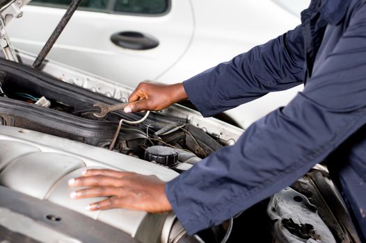 Closeup  of a hand holding a key on the engine of a broken car.