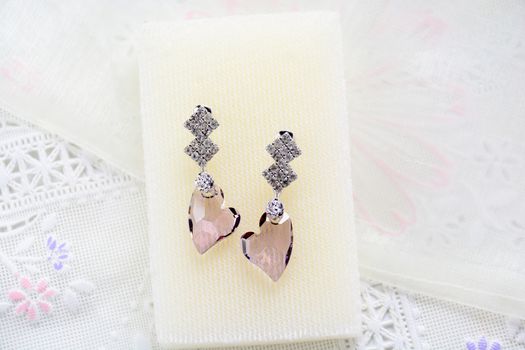 Crystal earrings on white fabric background
