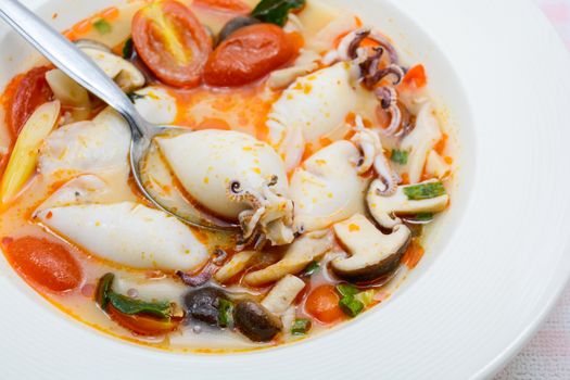 Squids and lemon grass spicy soup with mushrooms, tomatoes and herbs