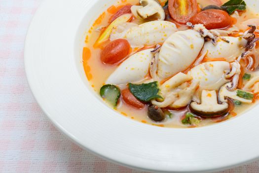 Squids and lemon grass spicy soup with mushrooms, tomatoes and herbs