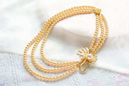 Pearl necklace on white fabric background
