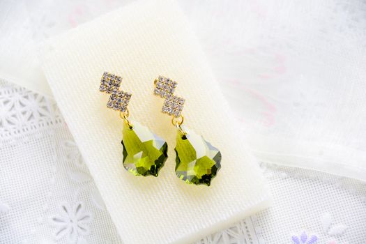Crystal earrings on white fabric background
