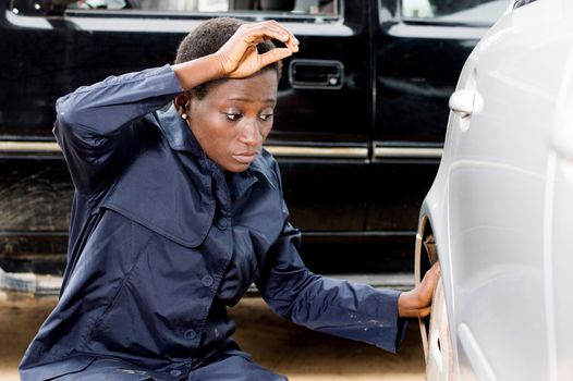 Closeup  of young woman mechanic changing the tire of a car in her garage.