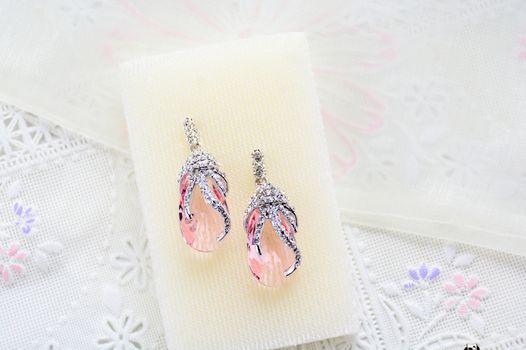 Crystal earrings on white fabric background
