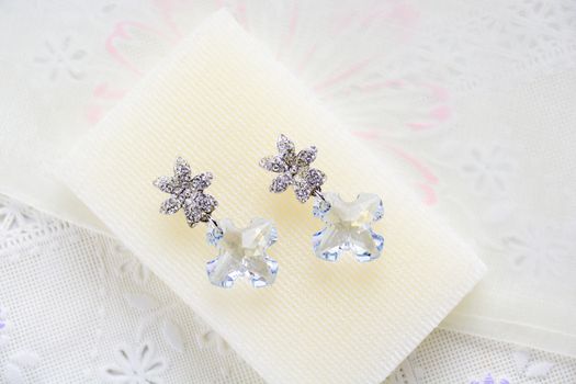 Crystal earrings on white fabric background
