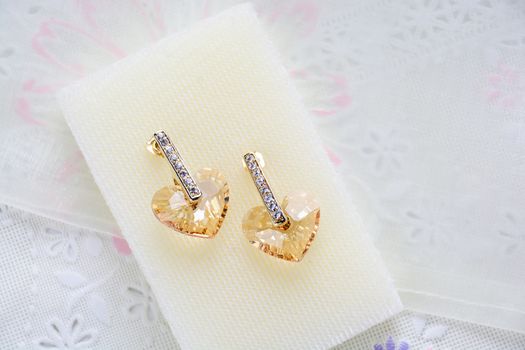 Crystal earrings on white fabric background
