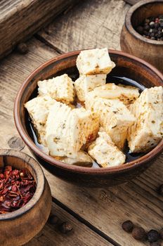 Feta cheese with herbs and garlic on old wooden background