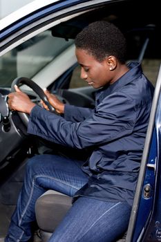 Young female mechanic seated at the wheel of this car controls its various pedals
