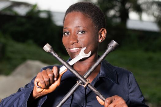 Young smiling mechanic showing her tools in her outdoor studio.