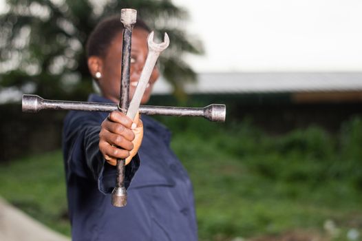 Young smiling mechanic showing her tools in her outdoor studio.