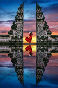 Young woman standing in temple gates at Lempuyang Luhur temple in Bali, Indonesia.