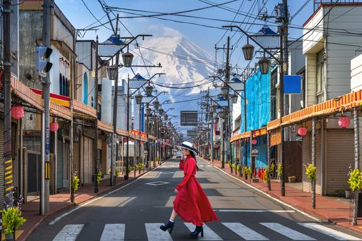 Woman walking on the road in Fujiyoshida with background of Fuji mountain, Japan.