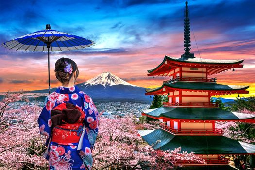 Cherry blossoms in spring, Asian woman wearing japanese traditional kimono at Chureito pagoda and Fuji mountain at sunset in Japan.