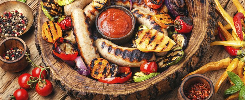 Grilled sausages and vegetables with sauce ketchup on a wooden table.Autumn food