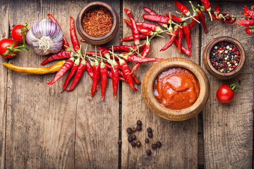 Chili peppers and chili sauce.Hot sauce from chilli peppers and tomatoes on wood background