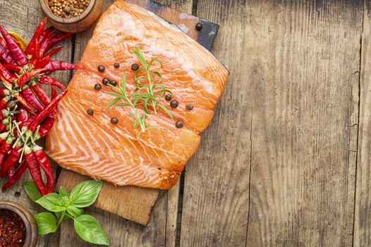 Raw salmon fillet with rosemary on wooden cutting board