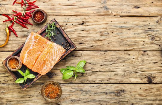 Raw salmon fillet with rosemary on wooden cutting board