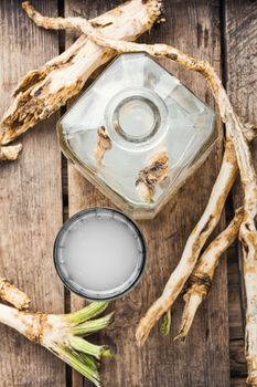Alcohol tincture from fresh horseradish root.Raw horseradish roots on wooden background