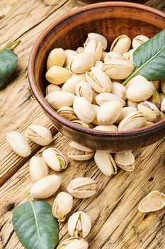 Bowl with pistachios on old wooden table.Nut