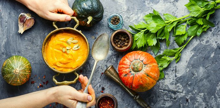 Vegetarian autumn pumpkin cream soup.Bowl of warm pumpkin soup in hands
