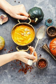 Vegetarian autumn pumpkin cream soup.Bowl of warm pumpkin soup in hands