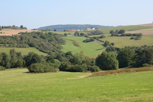 A hilly landscape with fields, meadows and forest