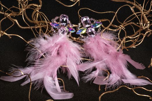 Jewelry. Women's jewelry.Earrings of pink feathers on a black background close-up, selective focus.