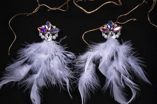 Jewelry. Women's jewelry.Earrings of pink feathers on a black background close-up, selective focus.