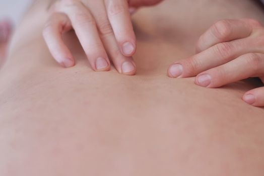 Close up image of physiotherapist massaging .Men's hands make massage. Care for the body. Back pain, back massage.