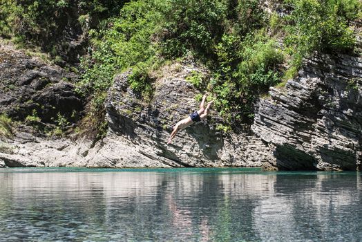 A man jumps from a cliff into a river. The abundance of nature. Albanian rivers.Cliff jumping into a mountain river .
