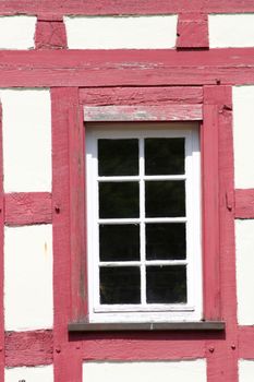 Timbered wall with red-colored wooden beams and white lattice windows