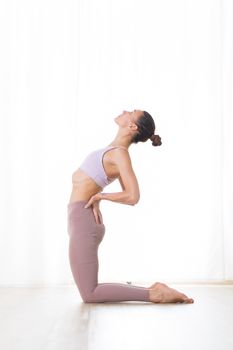 Portrait of gorgeous active sporty young woman practicing yoga in studio. Beautiful girl practice Ustrasana, camel yoga pose. Healthy active lifestyle, working out indoors in gym.