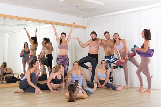 Group of young authentic real sporty attractive people in yoga studio having fun relaxing and socializing after hot yoga class. Healthy active lifestyle, working out in gym.