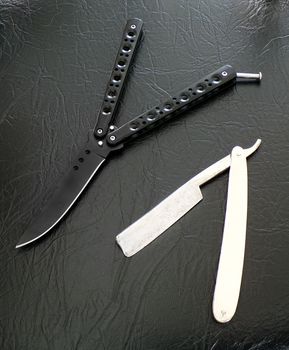 Butterfly knife and a manual razor on a black background. Bandit weapons for murder.