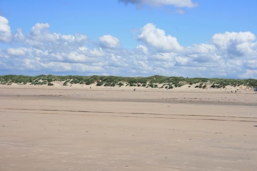 Sandy beach with sand dunes and blue sky in the background