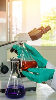 Laboratory beaker in analyst's hand in plastic glove