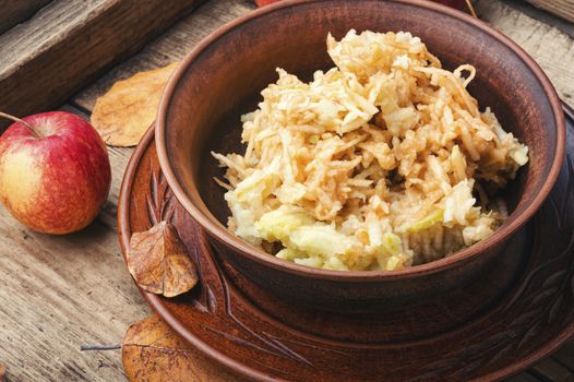 Grated ripe autumn apples in a plate on a wooden old table