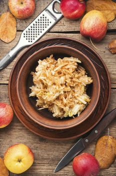 Grated ripe autumn apples in a plate on a wooden old table