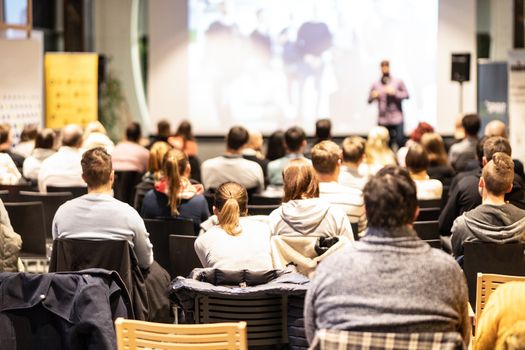 Speaker giving a talk in conference hall at business event. Audience at the conference hall. Business and Entrepreneurship concept. Focus on unrecognizable people in audience.